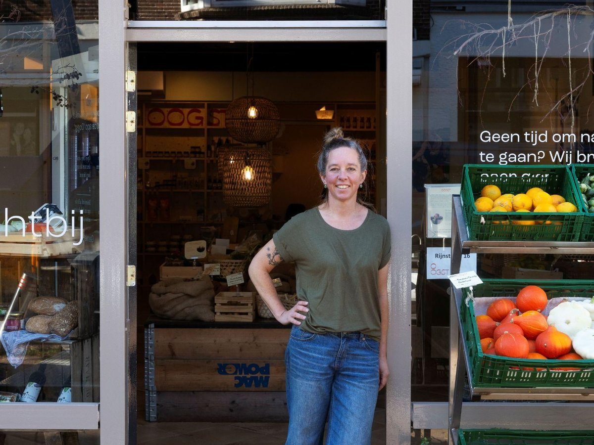 Ramona Schalkwijk staat lachend in de deuropening van boerenwinkel Oogst, naast kratten met groente en fruit